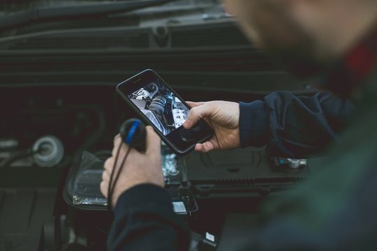 Mechanic taking picture of car engine with mobile phone