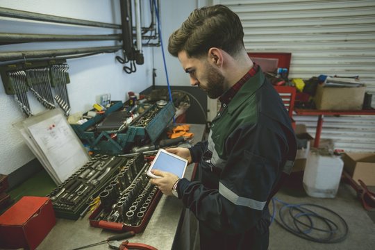 Side view of mechanic using digital tablet in garage