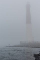 View of lighthouse with fisherman on a foggy morning