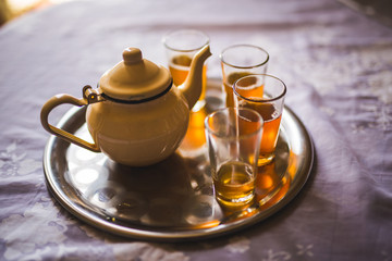 close up of a moroccan tea pot with glasses on a silver plate