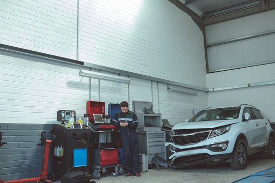 Mechanic using mobile phone while repairing car