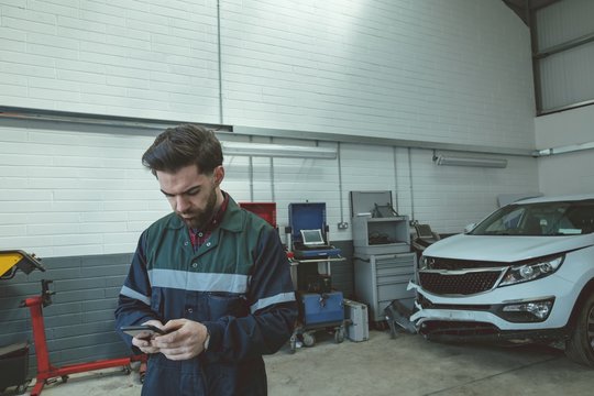 Mechanic using mobile phone while repairing car