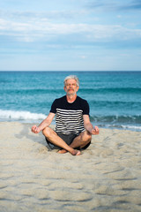 Senior man meditating on the beach