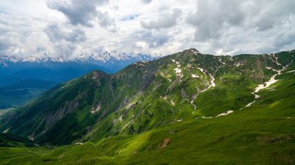 Fototapeta na wymiar Green mountains on a background of snowy peaks in Mestia