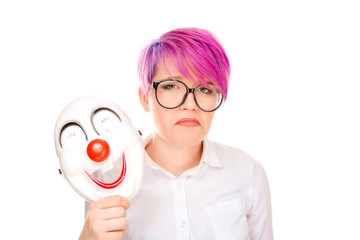 Upset worried woman with sad expression taking off laughing clown mask