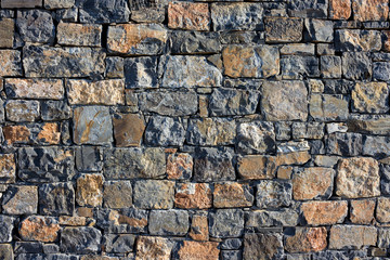 large wall of natural granite stones of different size and color, gray texture on a summer day, multi-colored granite natural stone, pieces of stone, splinters, texture pattern, stone wall, masonry