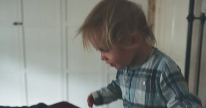 Little toddler boy throwing himself on a bed