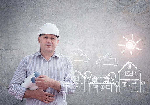 An engineer with construction plans on a concrete wall background. Real estate concept