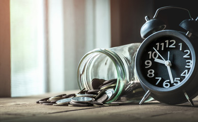 Coins with alarm clock - money savings concept.