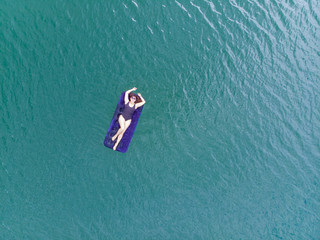 woman on mattress in azure water. overhead view. copy space