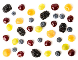 Blueberries, blueberries, red and yellow cherries are scattered on a white, top view. Fruit background assorted.