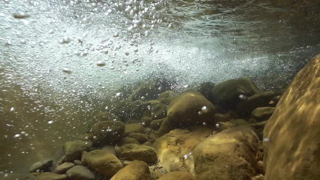 Air bubbles in a flowing river with rocks underwater, La Muga, Girona, Alt Emporda, Catalonia, Spain
