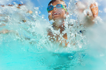 Happy boy having fun splashing water in the pool