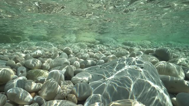 Pebbles below water surface in shallow water in the Mediterranean sea, underwater scene, natural sunlight, Javea , Alicante, Valencia, Spain
