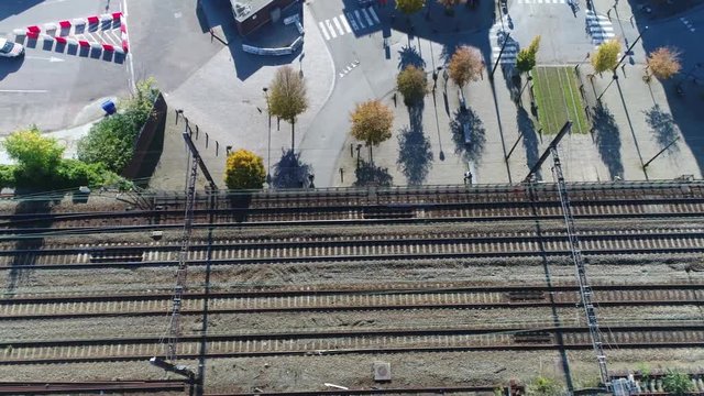 Urban aerial footage moving over tracks in city also showing road moving underneath the permanent way and traffic like automobiles and cyclists driving underneath the transportation infrastructure 4k