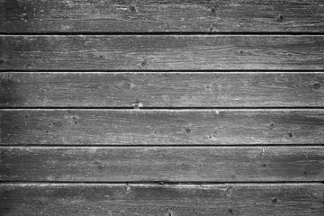 Full frame background of an old and faded wood board wall in black and white with vignette