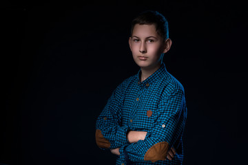 portrait of a teenager on a dark background in a blue shirt