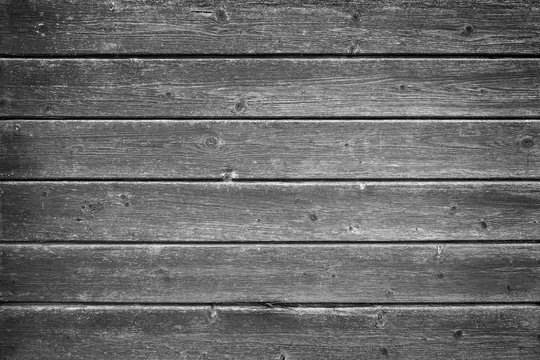 Full frame background of an old and faded wood board wall in black and white with vignette