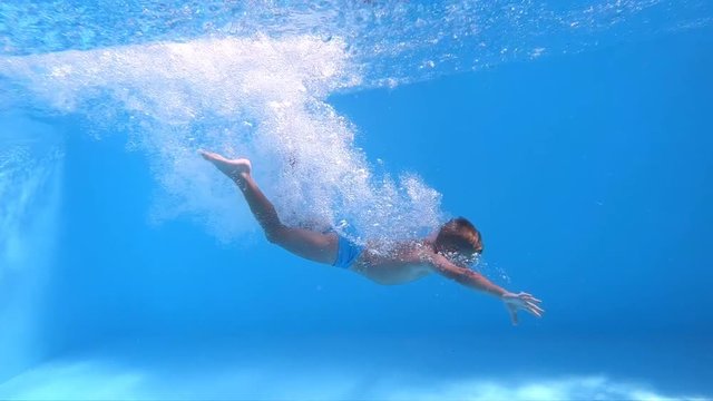 Jump into the water. Boy jumping into the water. Underwater shot. Slow motion.