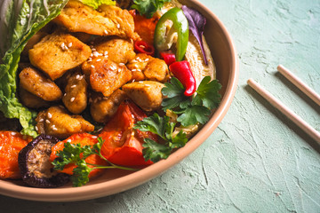 Pieces of fried chicken fillet in a bowl of vegetables.
