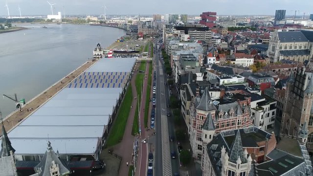 Urban aerial bird view footage of Antwerp Belgium moving over road alongside Scheldt River on left and showing rest of city architecture on right side in background showing US Army Monument 4k