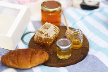 bottle with honey, bagel and honeycomb on a wooden plate