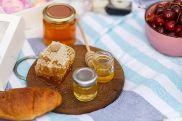 bottle with honey, bagel and honeycomb on a wooden plate