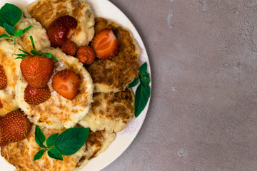Freshly baked cottage cheese pancakes with raisins, strawberry, mint leaf.