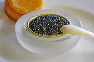 A tin of black sturgeon caviar with blinis and a mother-of-pearl spoon