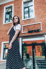 A beautiful girl in a long black sarafan walks down the street. loft style.