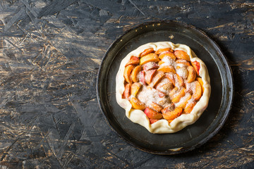  Homemade apricot galette made with fresh organic apricotes on wooden table, top view. Process of baking. Making dought. Hands with dought. Raw bakery. Open pie, apricot tart. Fruit bakery.