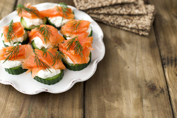 cucumber and salmon, small snacks on a plate. Copy space.
