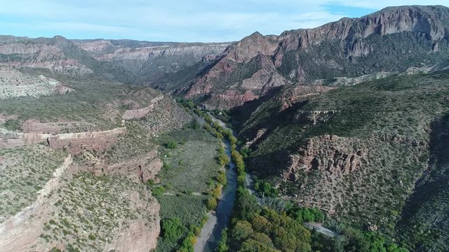 Aerial drone scene of Atuel river canyon in San Rafael, Mendoza, Cuyo Argentina. Camera moving upwards and forwards. Street next to the willows trees and river. Colorfull rocks.