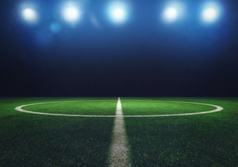 Fototapeta na wymiar Midfield of grass soccer field at night with headlights