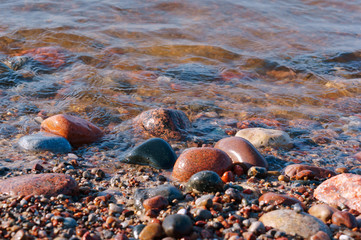 Rocky seashore. Sea wave and pebbles. Sea colored stones.