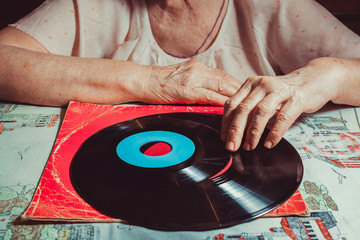 Elderly lady is holding a vinyl record.