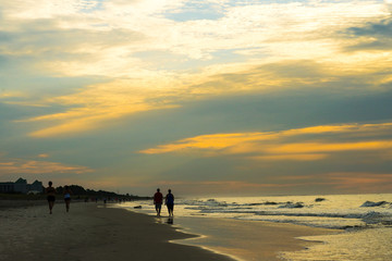 silhouette of people walking on beach at sunrise on Hilton Head Island SC.