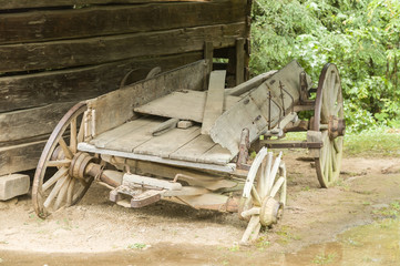 Fototapeta na wymiar Derelict farm cart beside an old, wooden building in a park in Tennessee, USA.