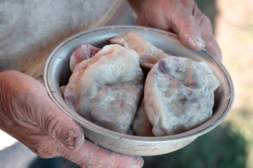 Dumplings with blueberries. Grandmother hands hold bowl of dumplings.