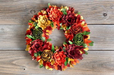 Colorful Wreath made of wooden flowers and leaves on vintage wood background