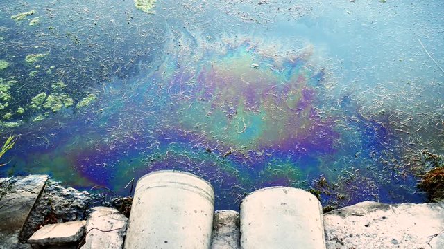 Sewer pipes at shore, stain of oil or fuel on water surface, nature pollution by toxic chemicals, dirty sea concept