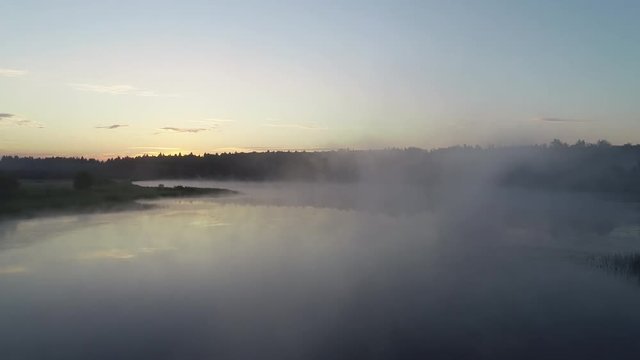 4k. Cinematic aerial footage. Forest lake in the morning fog, in the rays of the dawn sun. Drone footage.