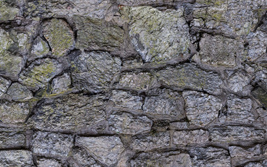 old gray weathered garden wall covered with moss rocks asymmetrical pattern