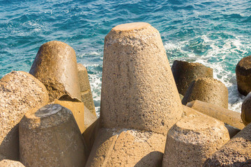 large cement block breakwater powerful protection of the coastline from the stormy waves of the sea against a background of azure water close-up