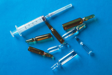 Medical ampoules and syringe isolated on a blue background