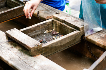 Gemstone panning with a sluice box. Sifting for stones and fossils at the mining sluice. Kids education.