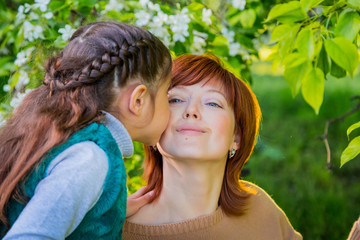 Mother and daughter having fun near blossom apple trees