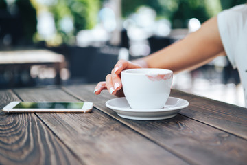 White cup of coffee with lipstick. On the table a cup of coffee and a telephone