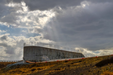 Concrete dam spillway with stormy skies