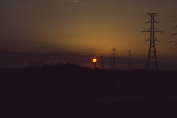 high voltage electric poles with sunset and evening sky background, filtered tones